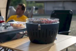 LotusGrill XL Hybrid Houtskoolbarbecue - Rood -Campingreeksen Winkel lotusgrill in gebruik met toppy shirtje 2